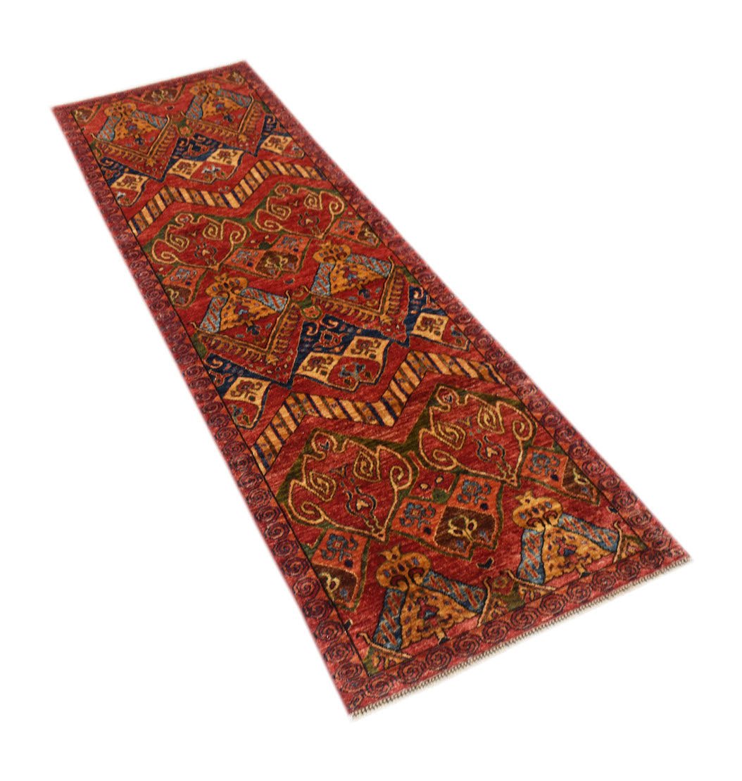 An Afghan Chobi runner rug featuring traditional geometric patterns in warm red and earthy tones.