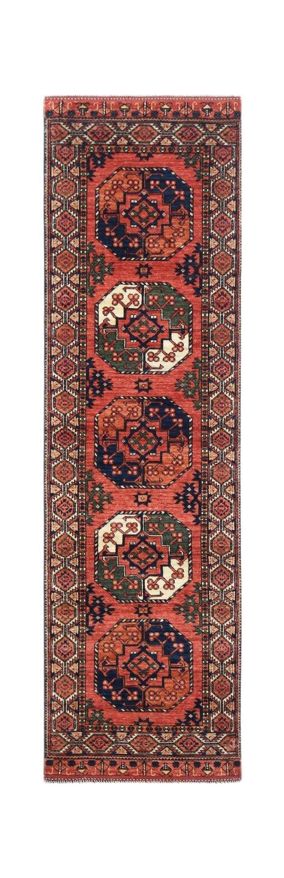 A handmade Afghan Chobi runner rug featuring repeating octagonal motifs in red, blue, and green.