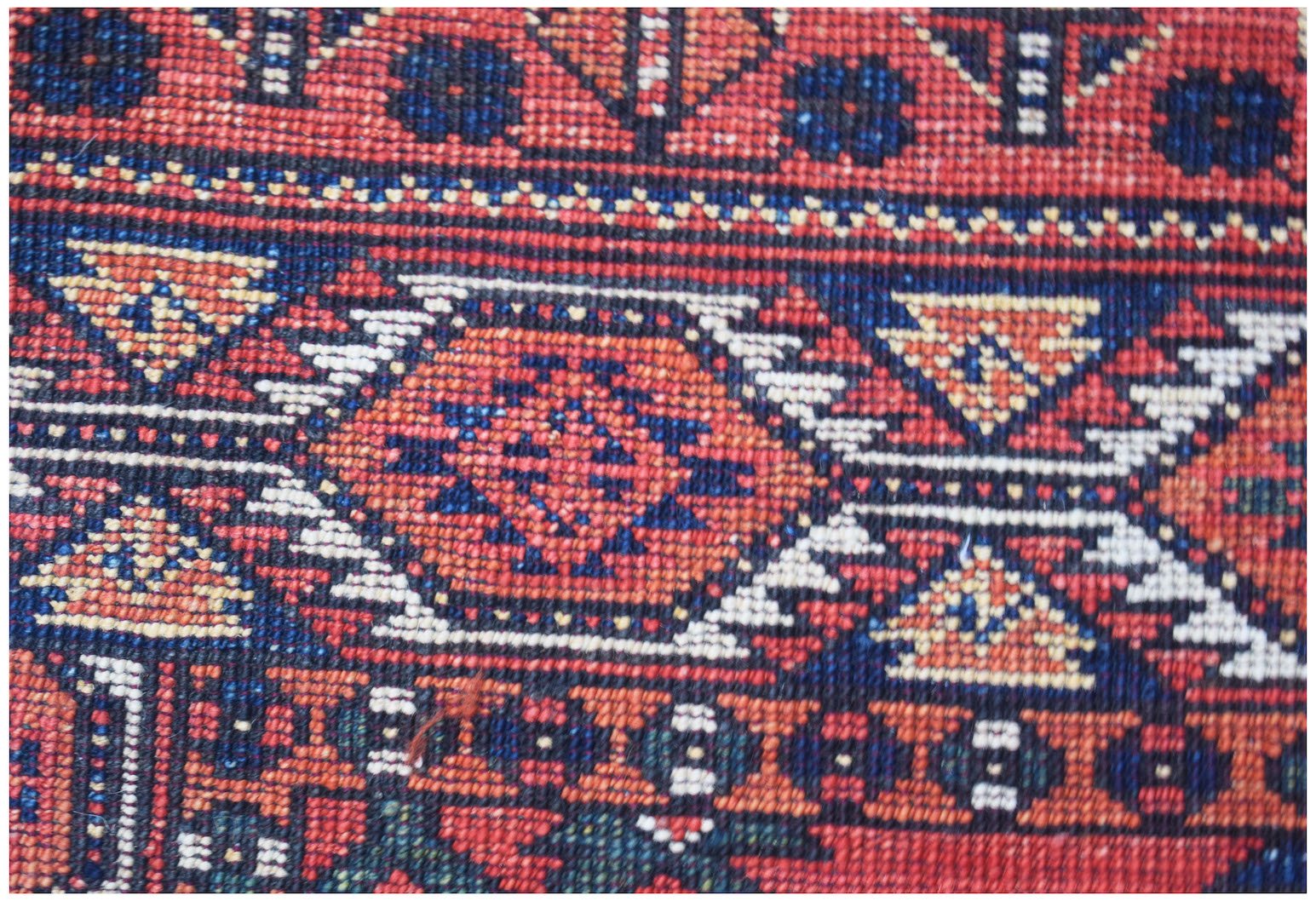 A close-up of a handwoven Afghan Chobi runner featuring traditional geometric patterns in red and blue.