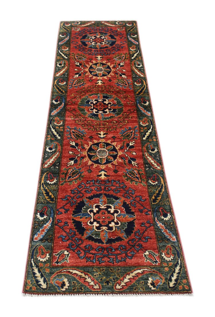 A handmade Afghan Chobi runner rug featuring traditional floral medallions on a red background.