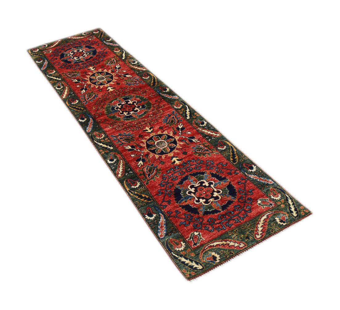 A handmade Afghan Chobi runner rug featuring traditional floral motifs in red and green tones.