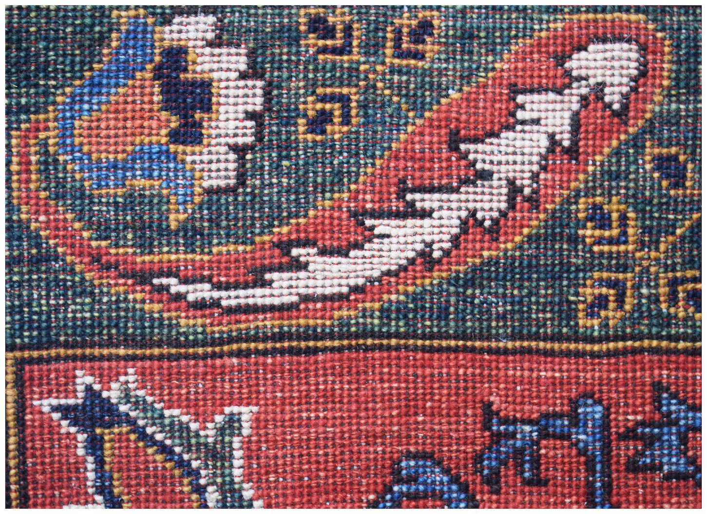 A close-up of an Afghan Chobi runner featuring intricate traditional patterns in red and blue wool.