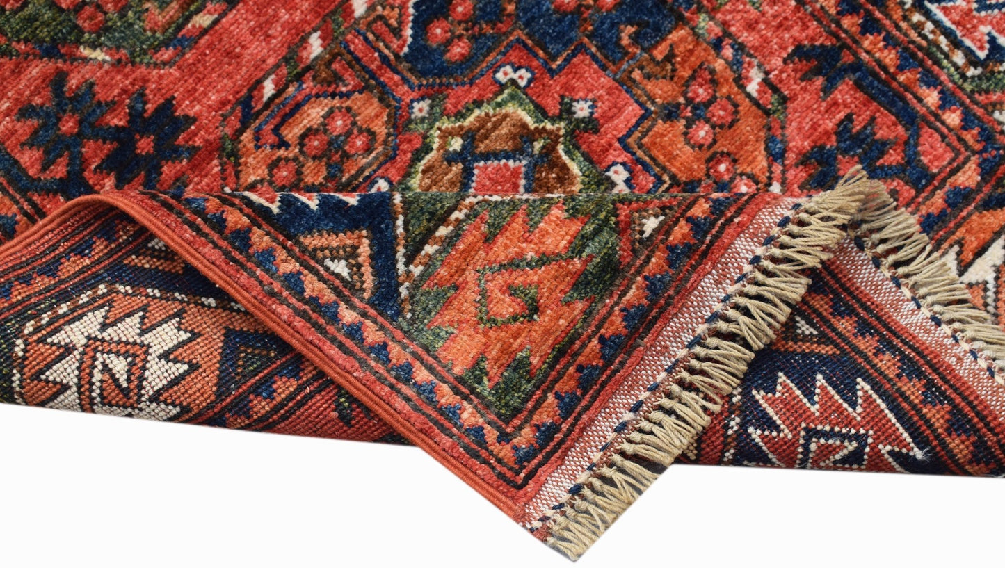 A handwoven Afghan Chobi runner featuring a traditional geometric pattern in red and blue wool.