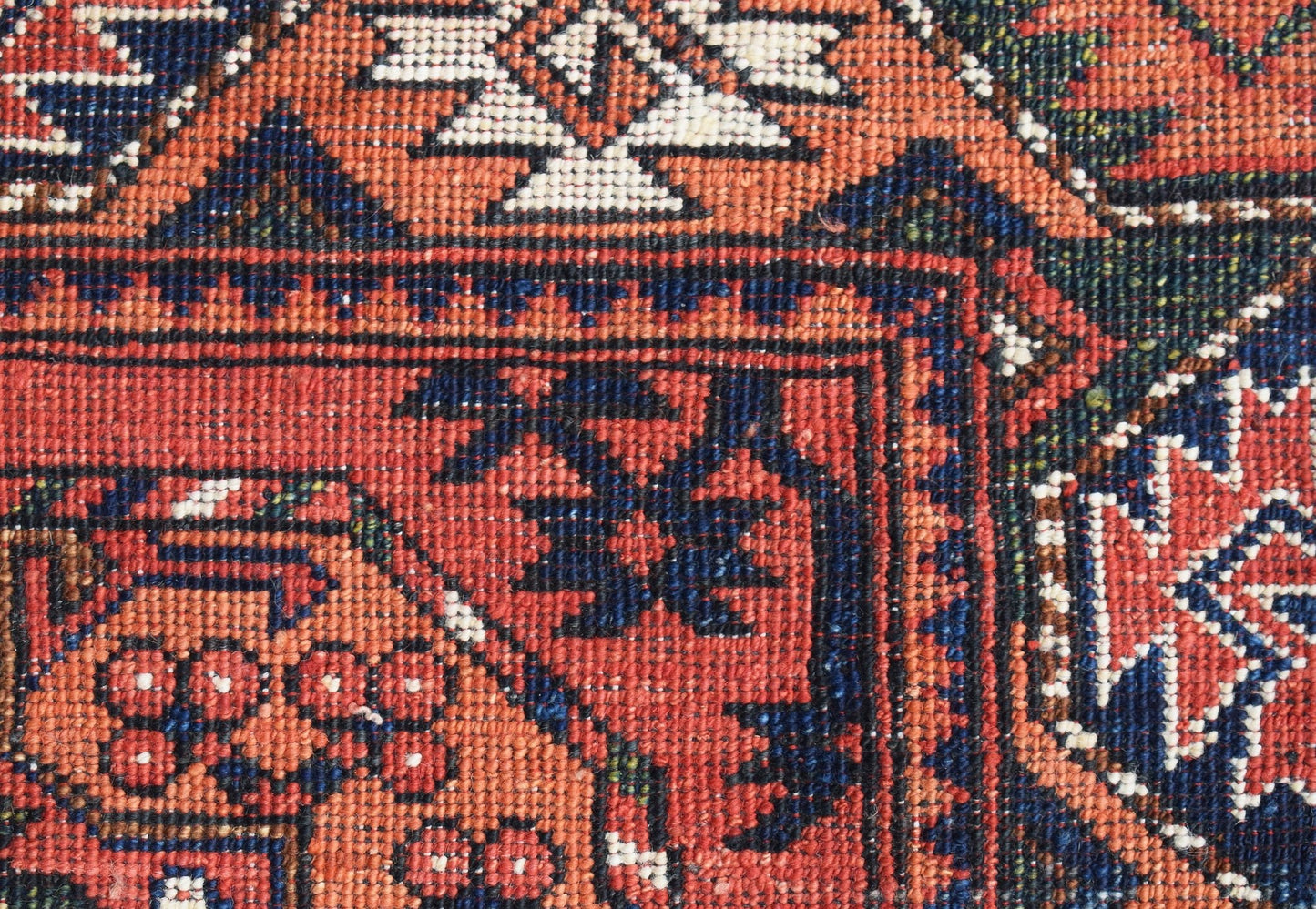 A close-up of a handwoven Afghan Chobi runner featuring intricate geometric patterns in red and blue.