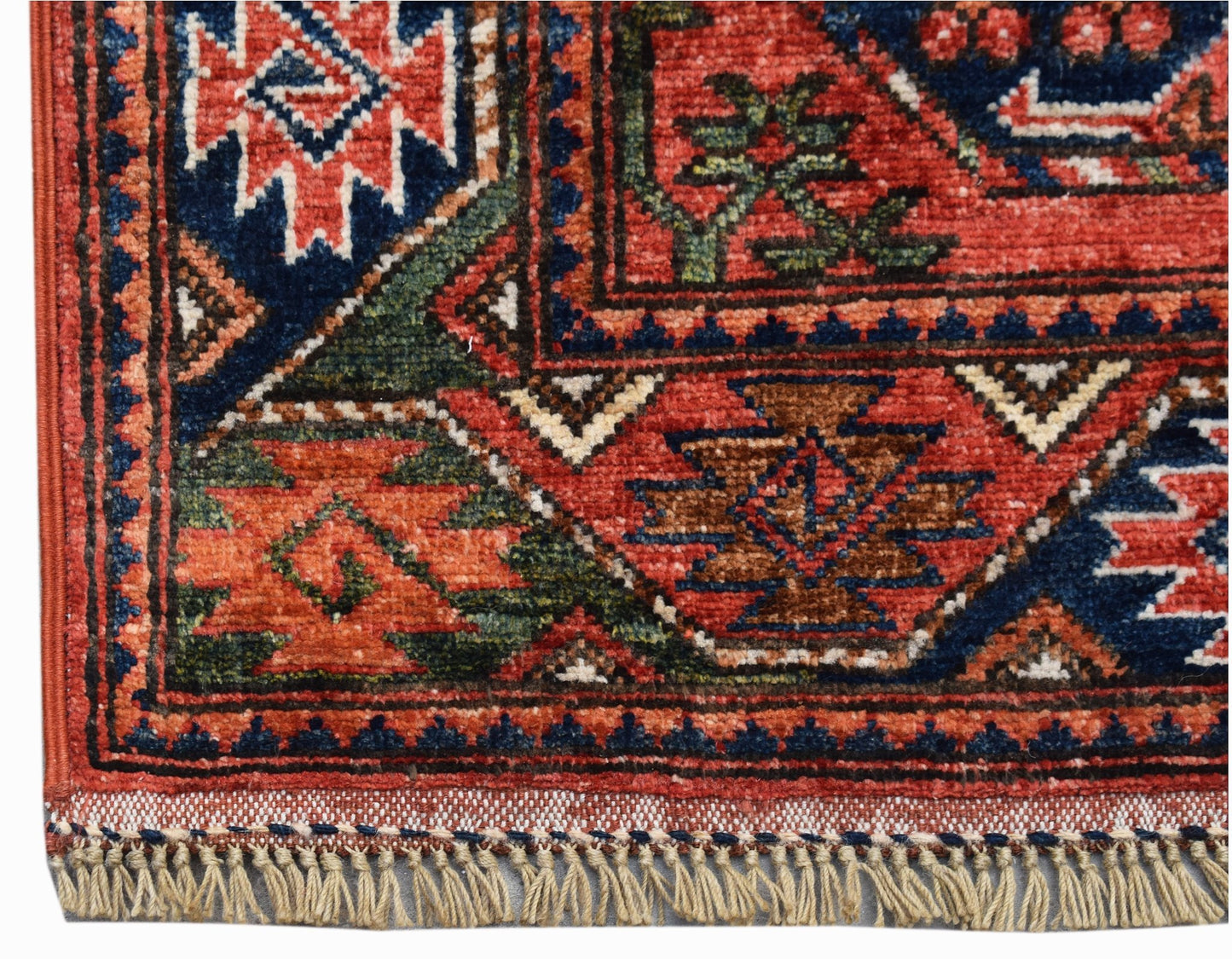 A close-up of a handwoven Afghan Chobi runner featuring traditional geometric patterns in red and blue.