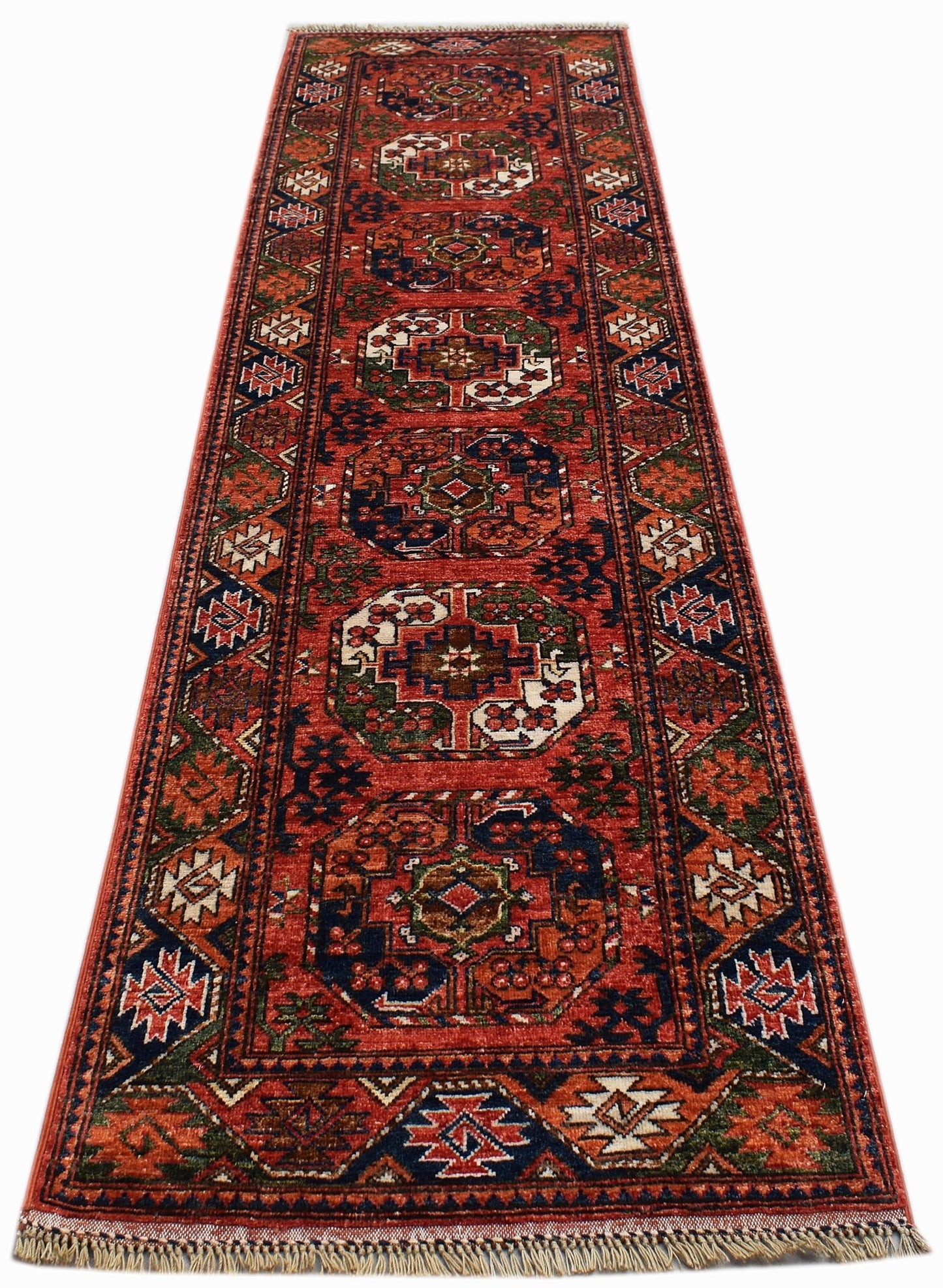 A handwoven Afghan Chobi runner rug featuring geometric medallions in red, blue, and cream tones.