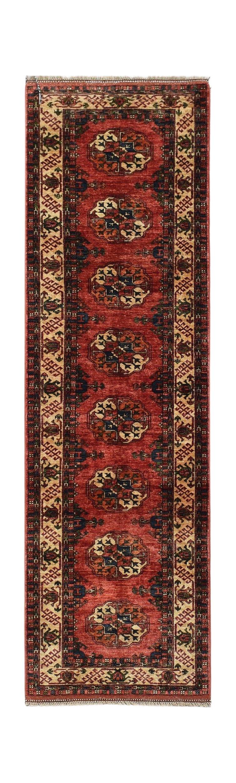A handmade Afghan Chobi runner rug featuring repeating geometric medallions on a red field.