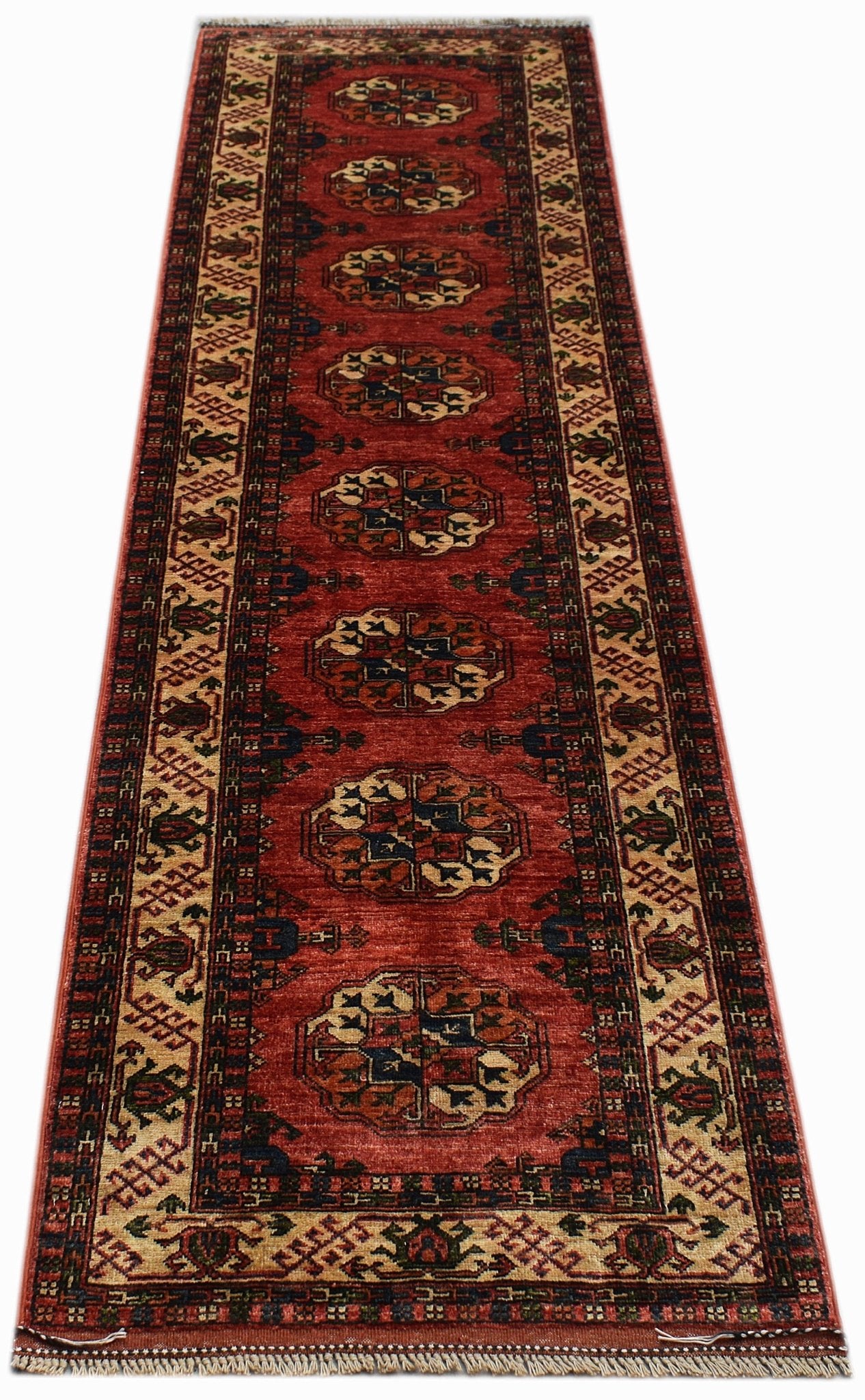 A handmade Afghan Chobi runner rug featuring a repeating geometric medallion pattern in red wool.