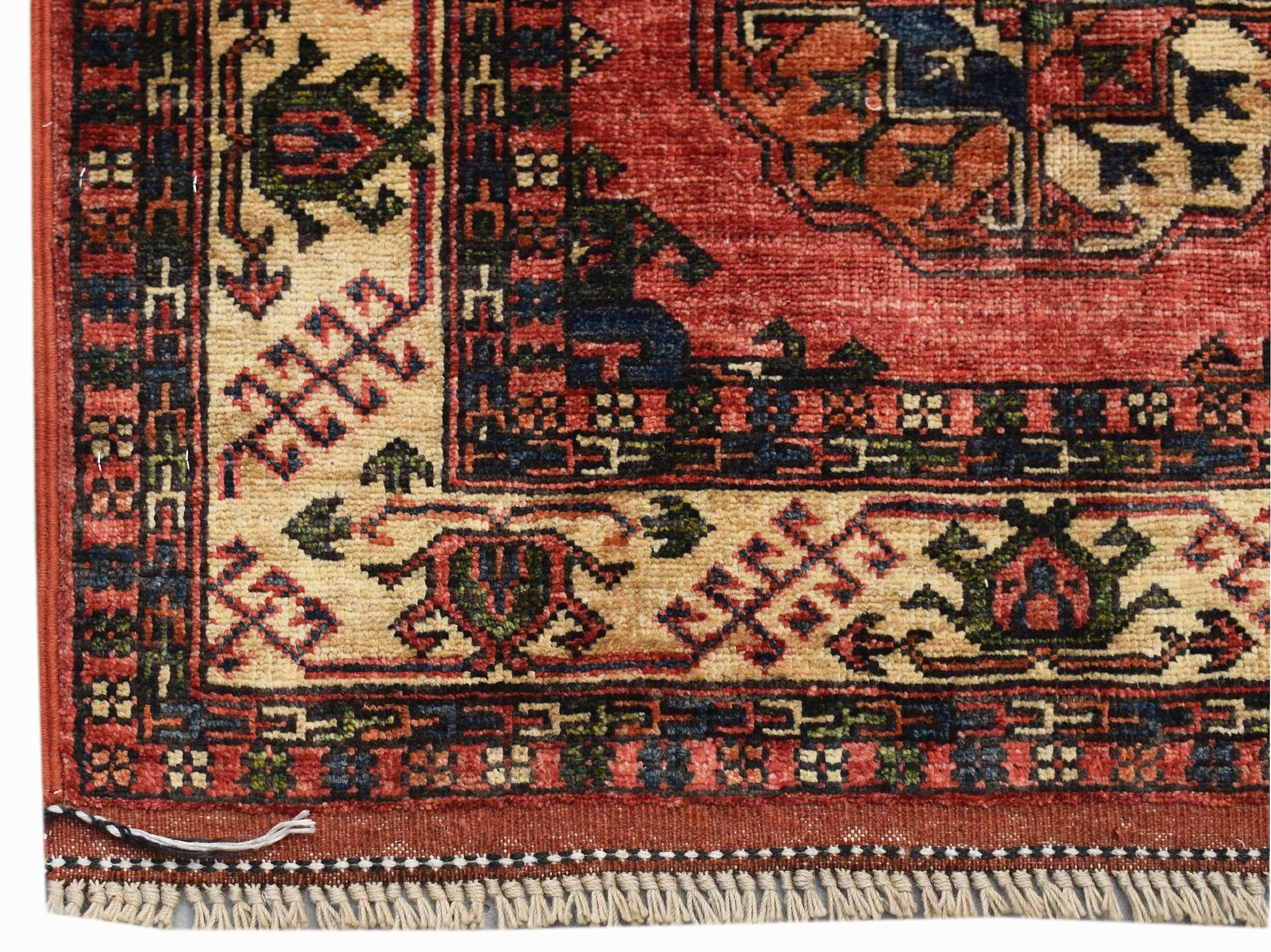 A corner view of a handwoven Afghan Chobi runner featuring traditional geometric patterns in red and cream.