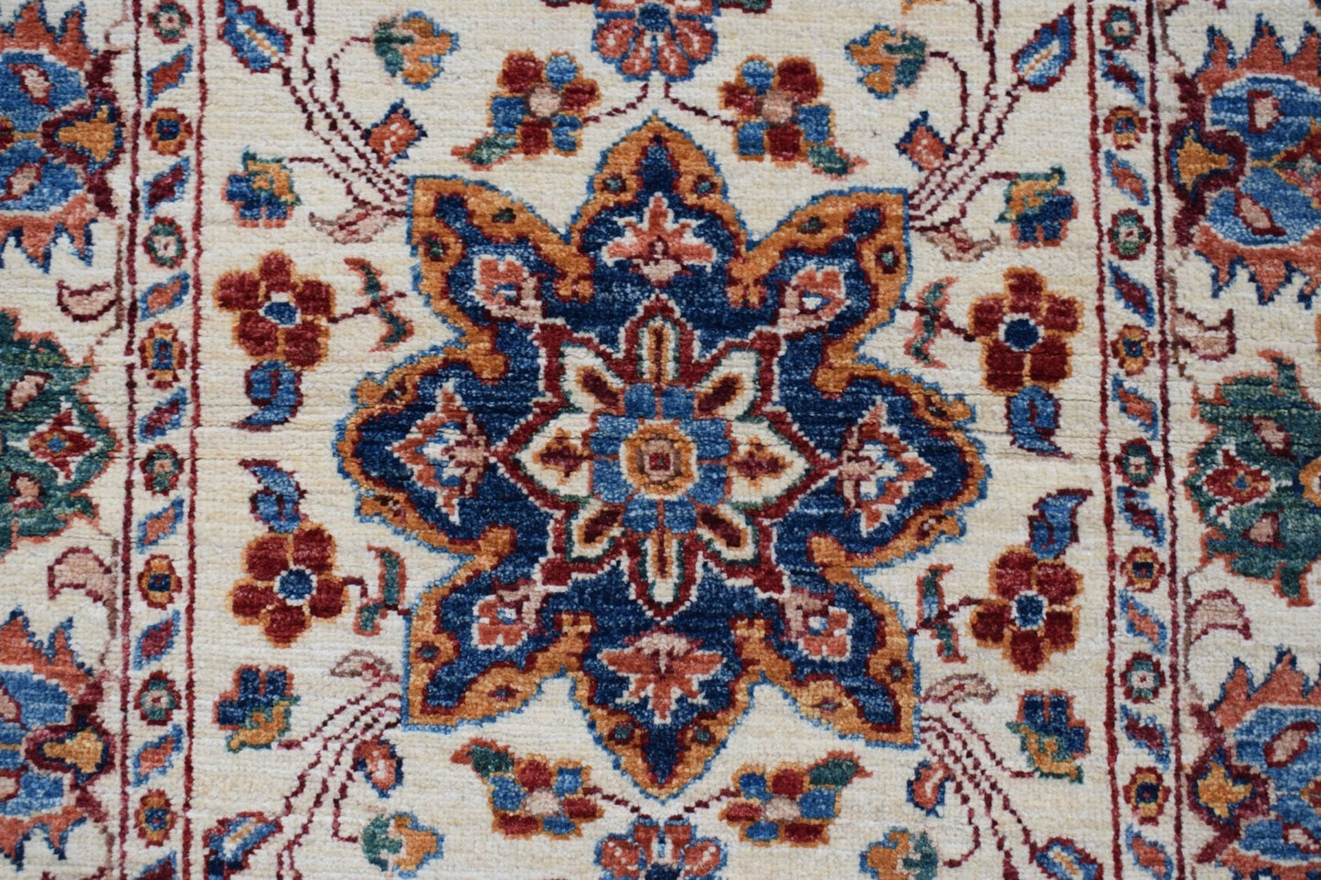 A handmade Afghan Chobi runner featuring a central floral medallion in blue, red, and gold tones.
