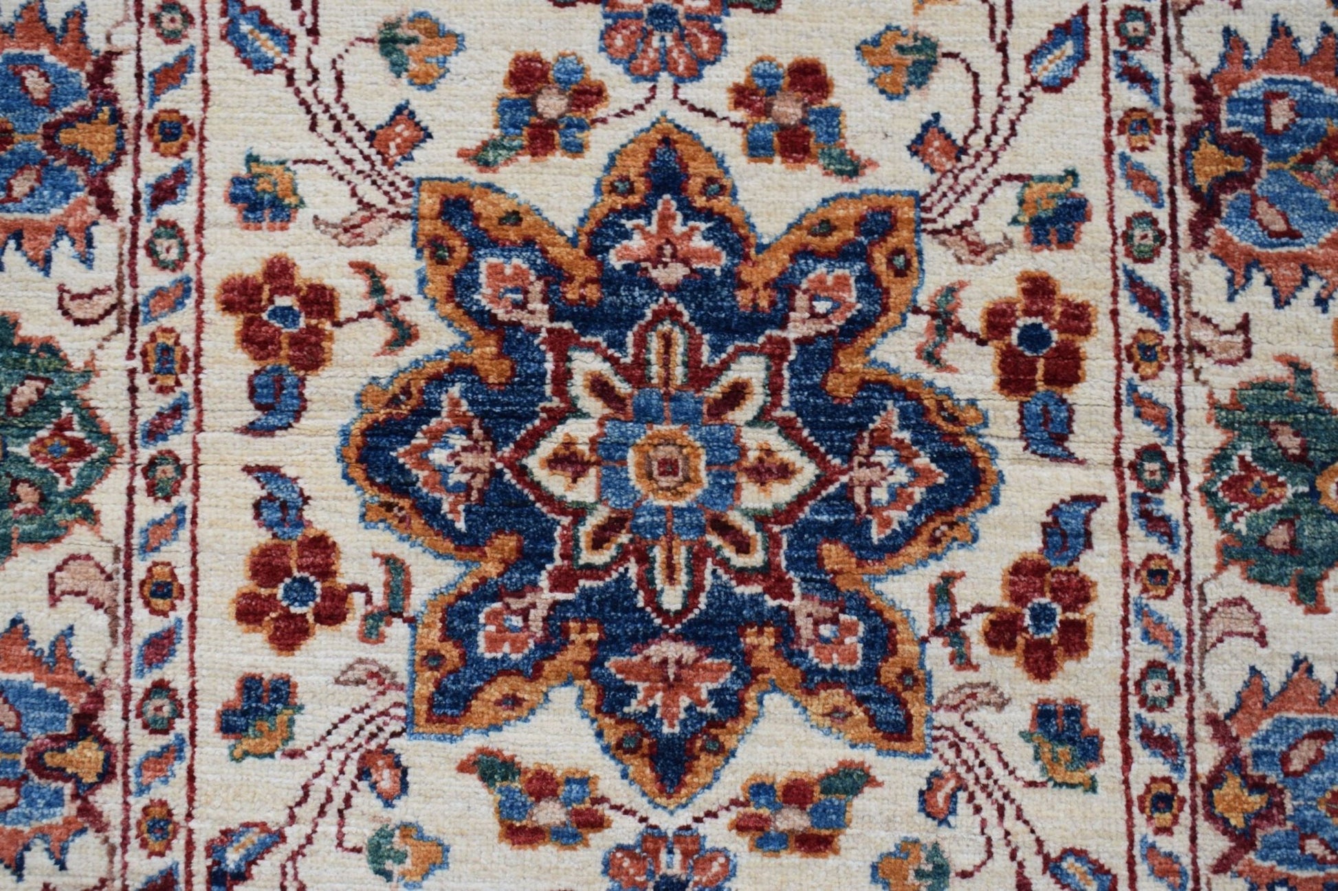 A handmade Afghan Chobi runner featuring a central floral medallion in blue, red, and gold tones.
