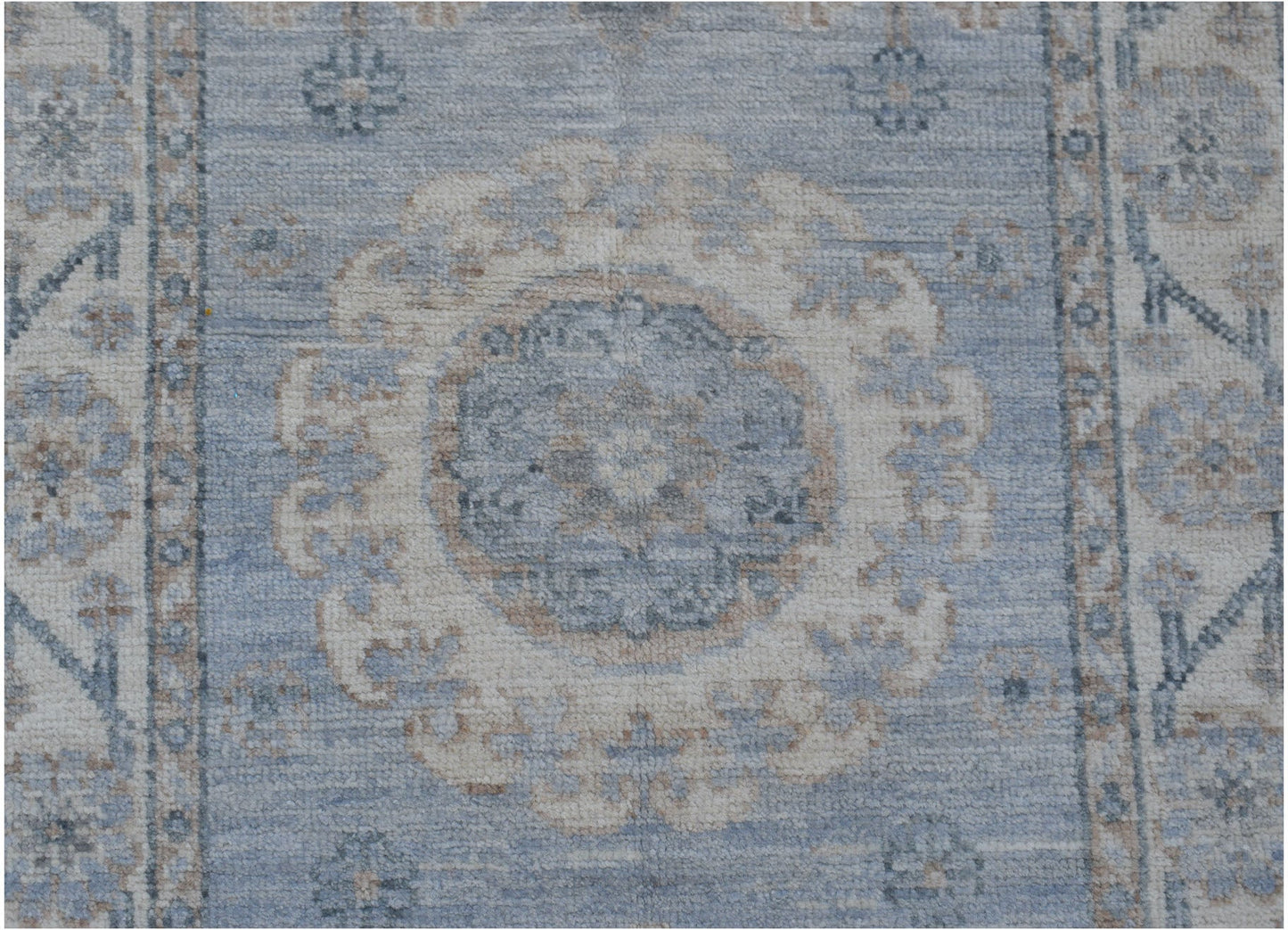 A handmade Afghan Chobi runner rug featuring a central floral medallion in blue and beige tones.