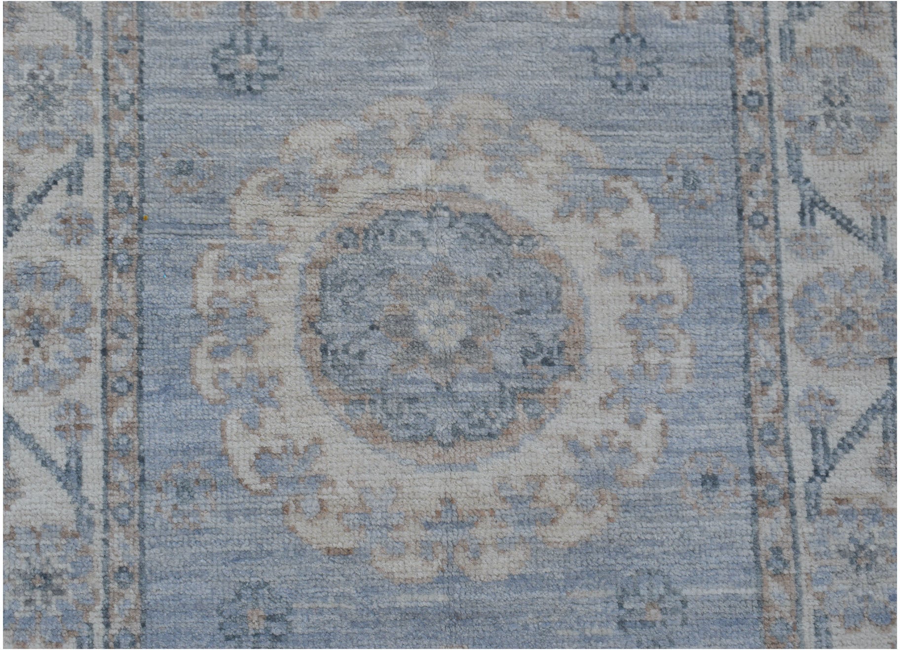 A handmade Afghan Chobi runner rug featuring a central floral medallion in blue and beige tones.