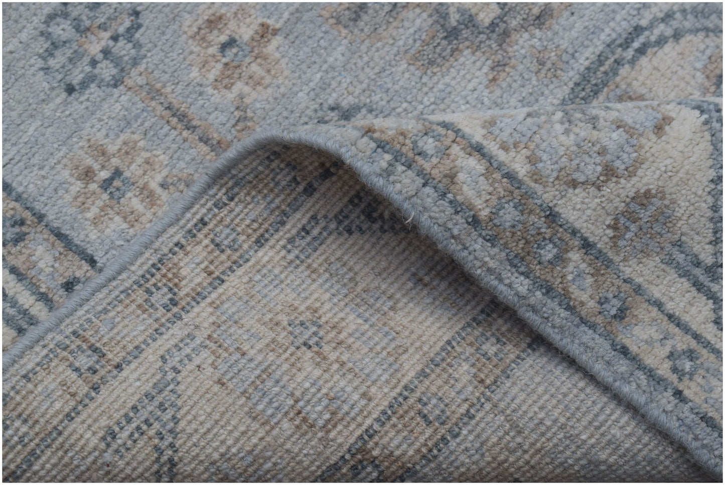 A corner of a handmade Afghan Chobi runner featuring a traditional pattern in muted blue and beige.