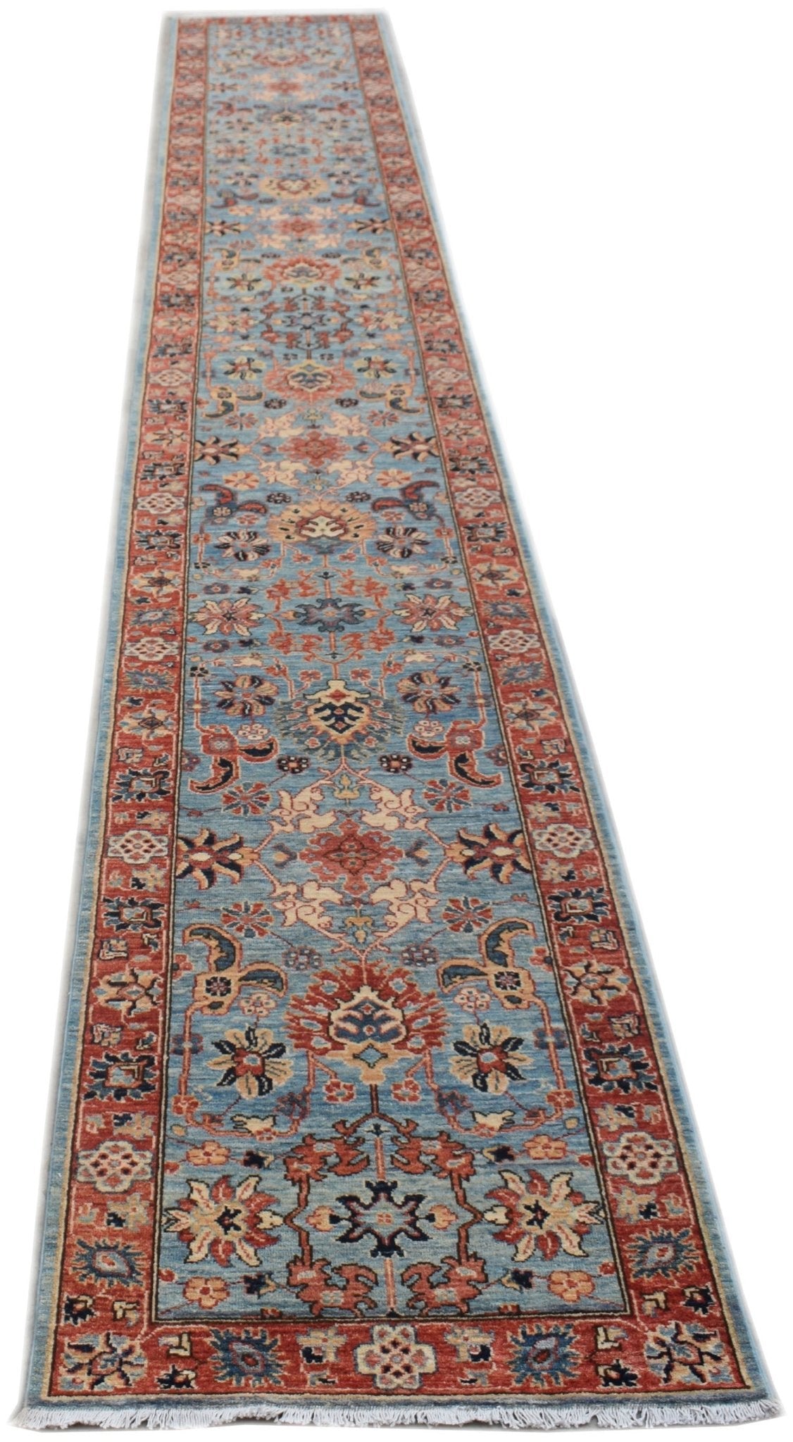 A long, handmade Afghan Chobi runner rug featuring a traditional floral pattern in blue and red.