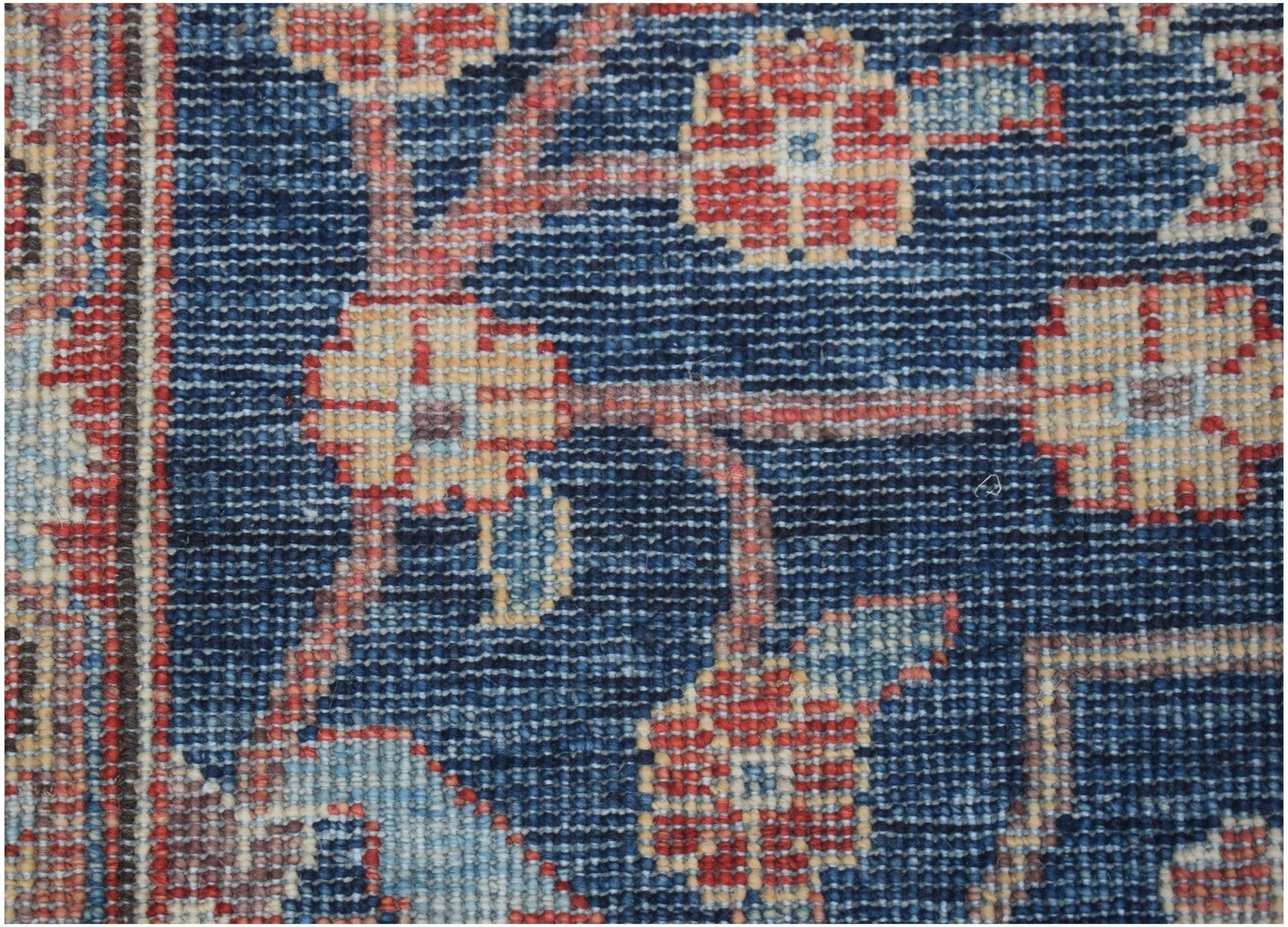 A close-up of a handmade Afghan Chobi runner featuring floral patterns in red and cream on blue.