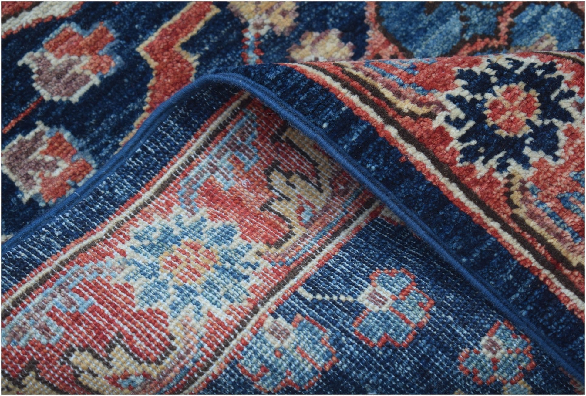 A close-up of a handmade Afghan Chobi runner featuring traditional floral patterns in blue and red.