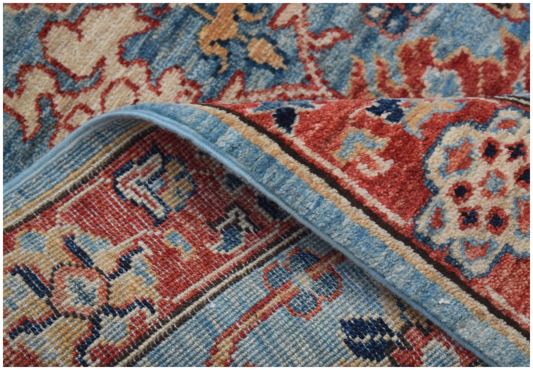 A close-up of a handmade Afghan Chobi runner featuring traditional floral patterns in red and blue.