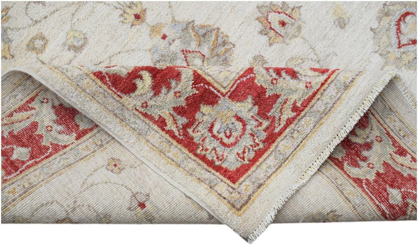 A handwoven Afghan Chobi rug with a cream field and a red floral border, shown folded.