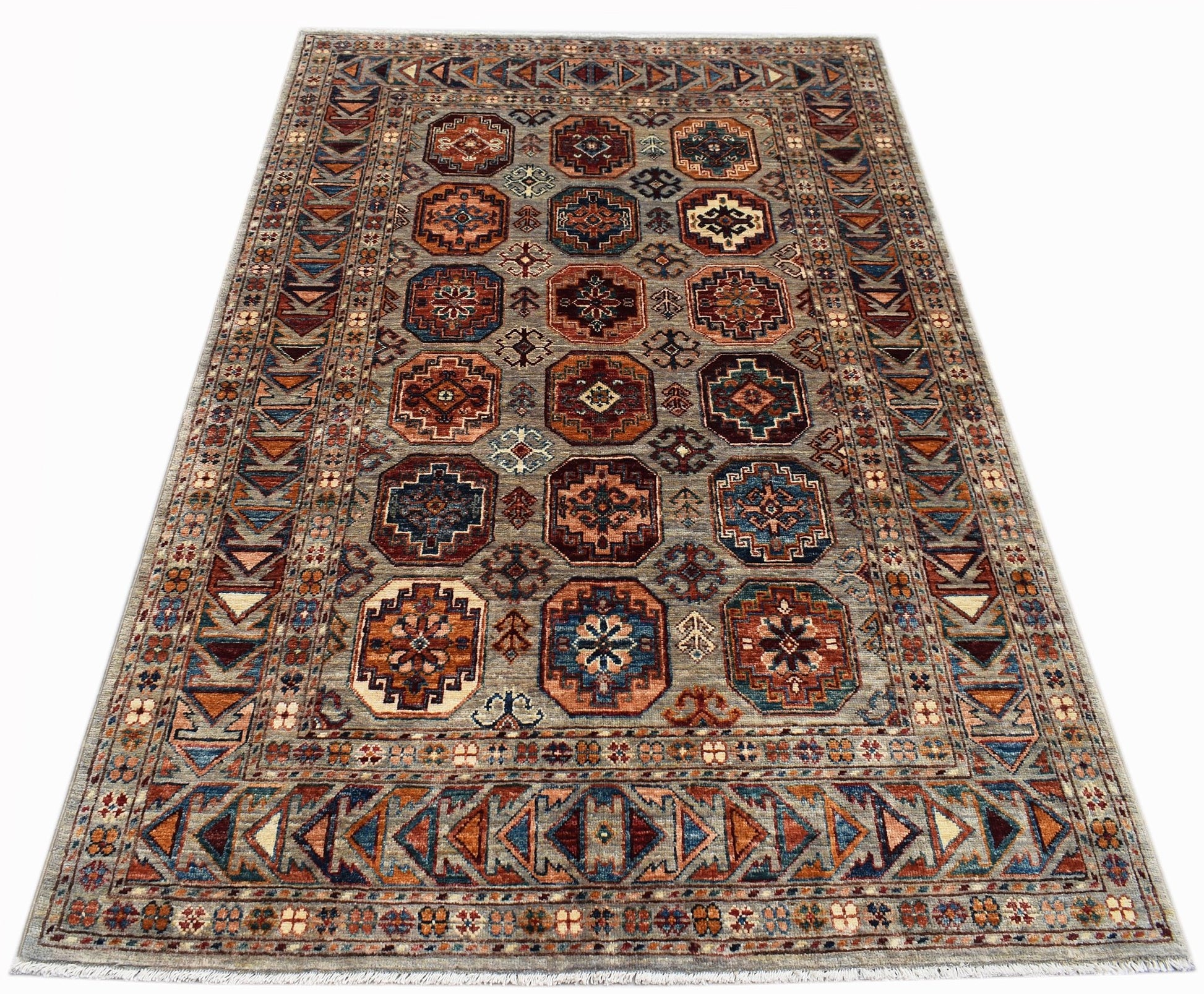 A rectangular Afghan Chobi rug featuring a geometric pattern of octagonal motifs in earthy tones.