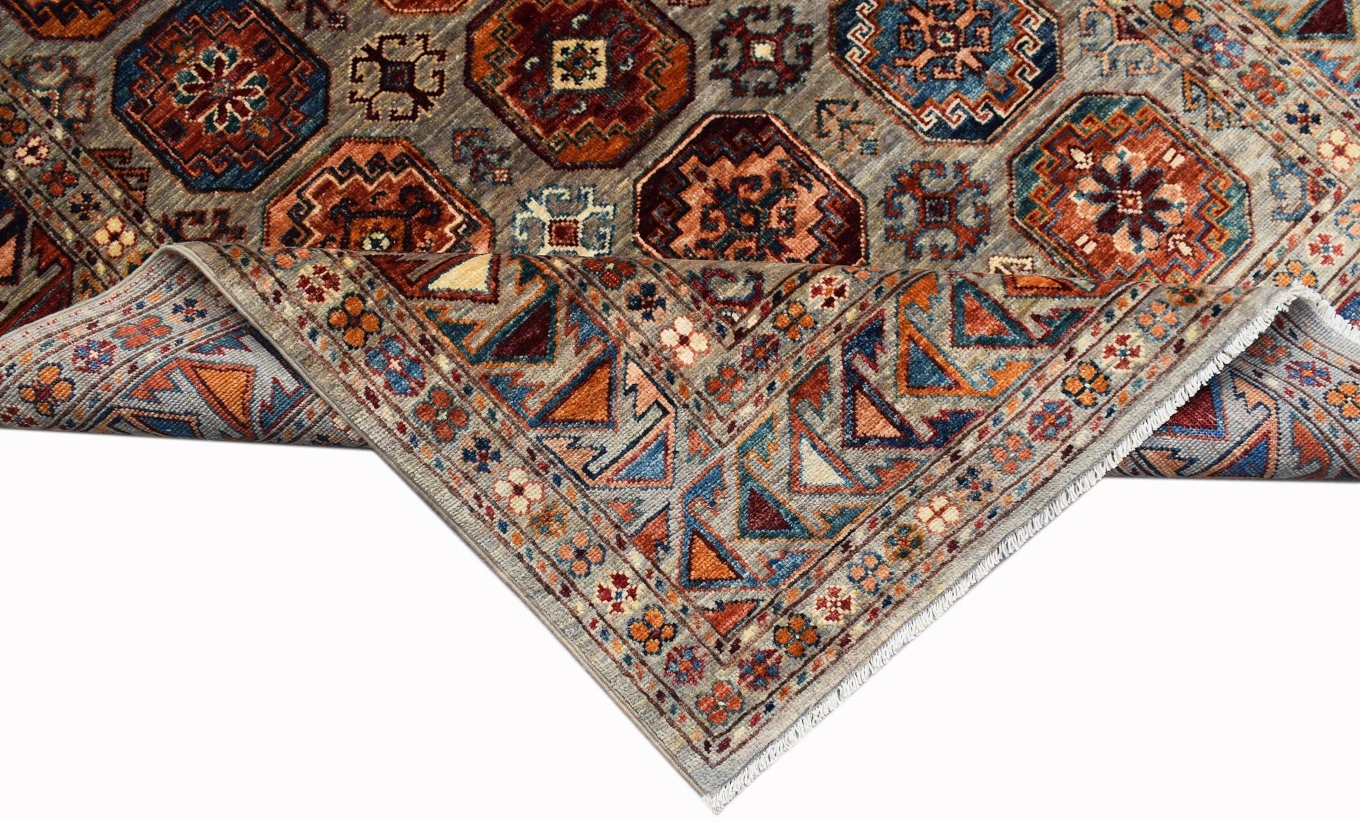 A handwoven Afghan Chobi rug featuring geometric patterns in earthy tones on a grey background.