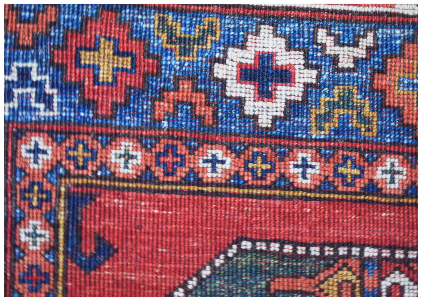 A close-up of a handmade Afghan Chobi rug featuring intricate geometric patterns in red and blue.