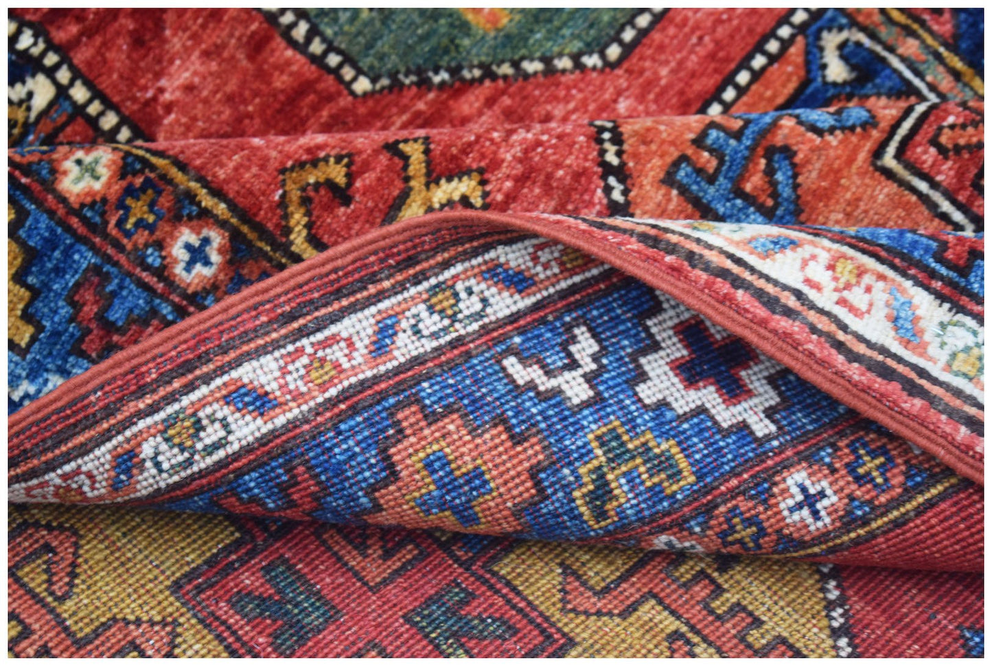 A handwoven Afghan Chobi rug featuring traditional geometric patterns in red, blue, and gold.
