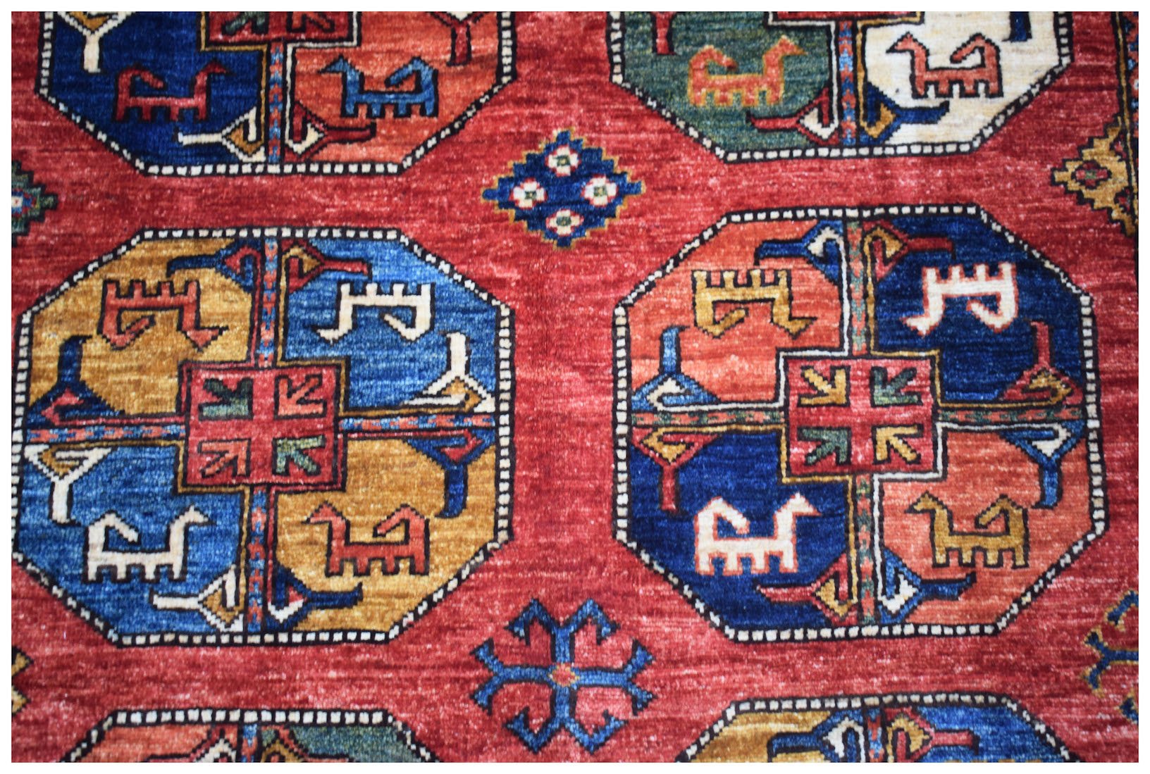 Handwoven Afghan Chobi rug featuring a geometric pattern of octagonal medallions on a red field.