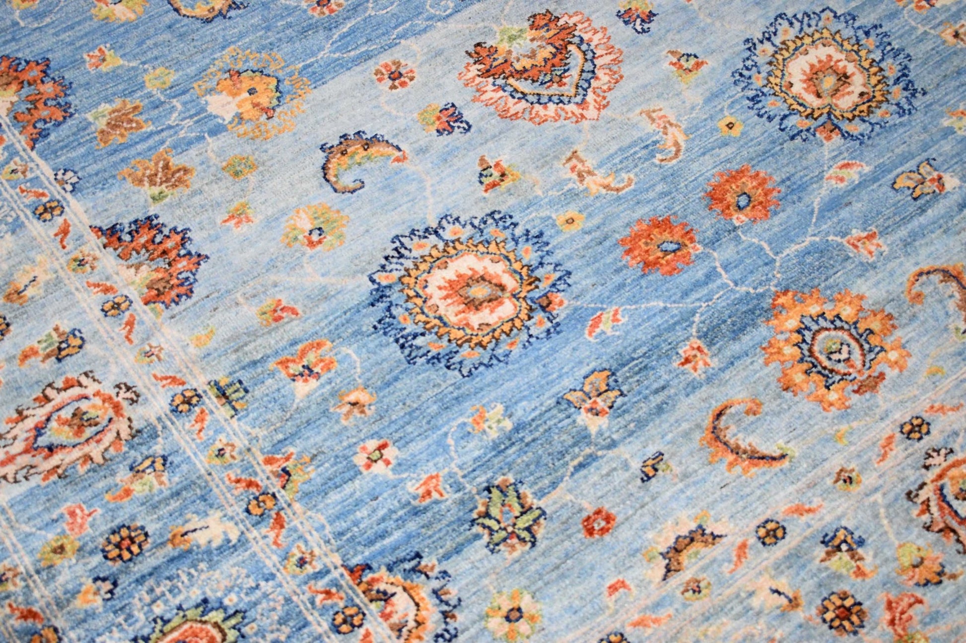 A handmade Afghan Chobi rug featuring intricate floral patterns in orange and blue tones.