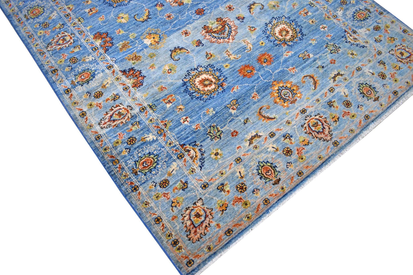 A handmade Afghan Chobi rug featuring intricate floral patterns in shades of blue and orange.