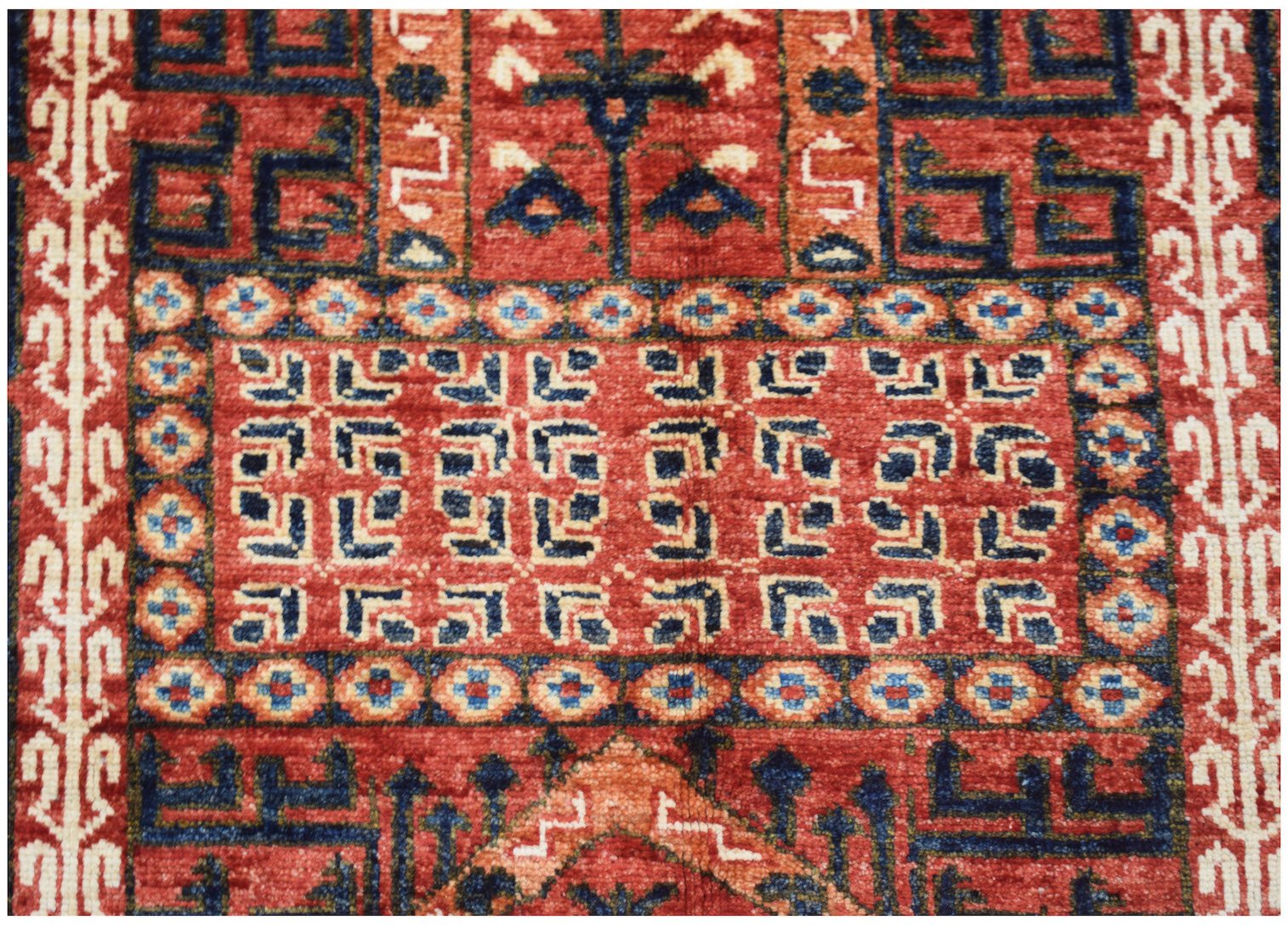 A handmade Afghan Chobi rug featuring intricate geometric patterns in shades of red and blue.