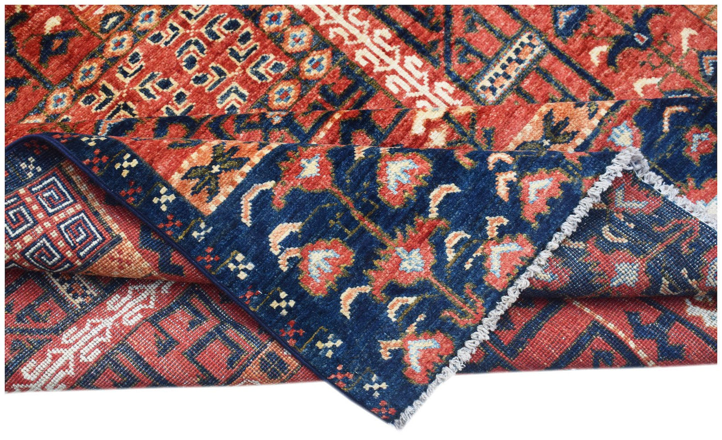 A folded Afghan Chobi rug featuring traditional geometric and floral patterns in red and blue.