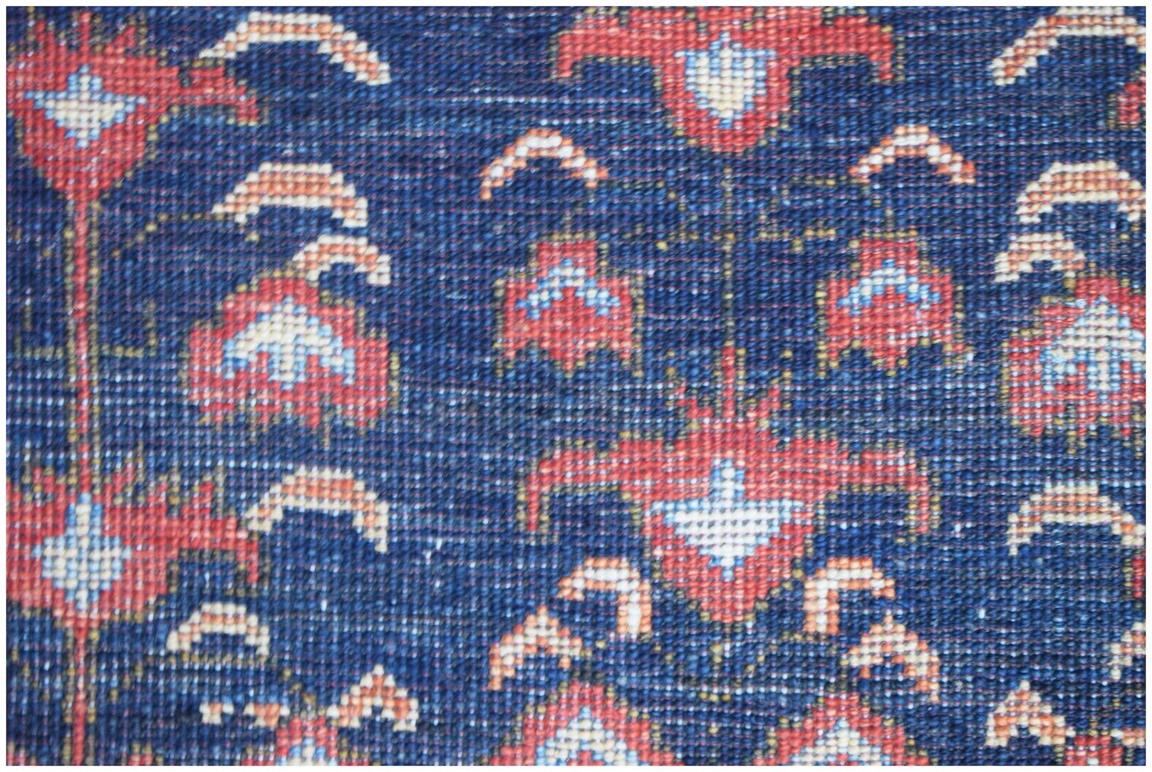 A close-up of a handmade Afghan Chobi rug featuring a traditional floral pattern in red and blue.