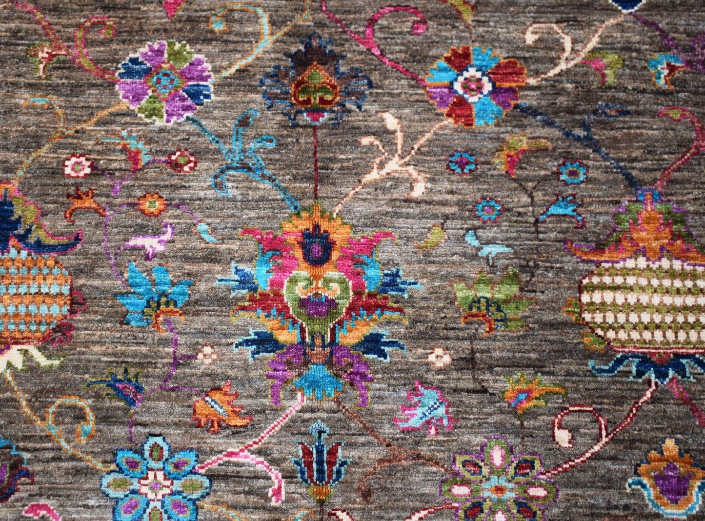 A handmade Afghan Chobi rug featuring a vibrant floral pattern on a textured grey wool background.