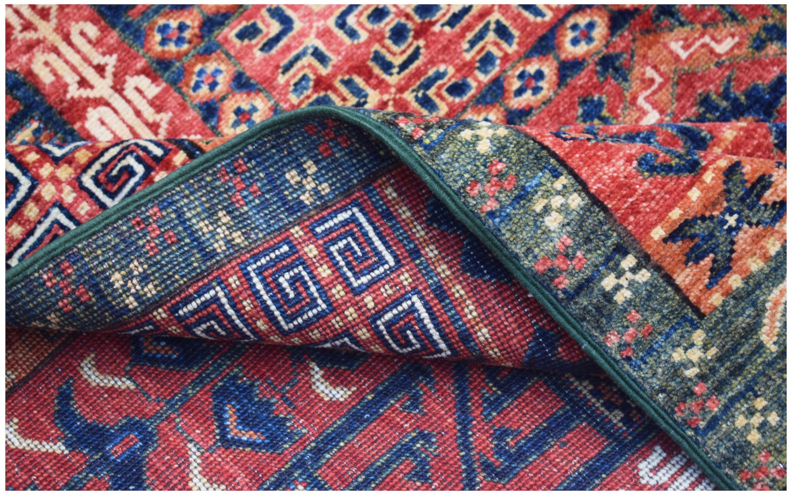 A handwoven Afghan Chobi rug featuring traditional geometric patterns in red, blue, and green.