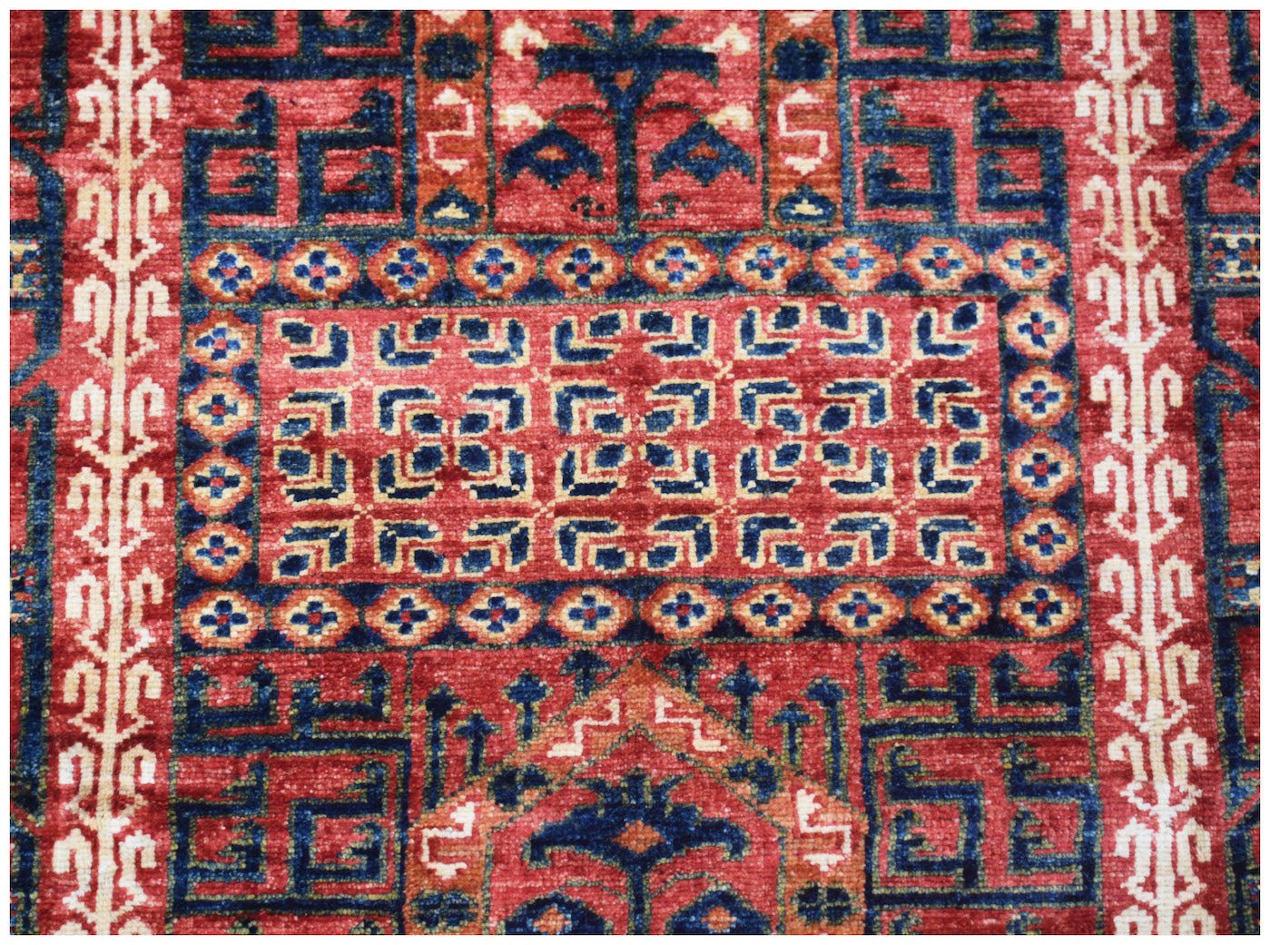 A handmade Afghan Chobi rug featuring intricate geometric patterns in red, blue, and cream tones.