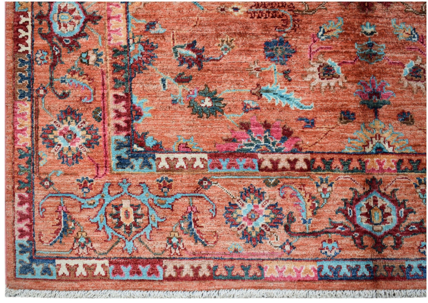 A handmade Afghan Chobi rug featuring intricate floral patterns in shades of orange, blue, and pink.