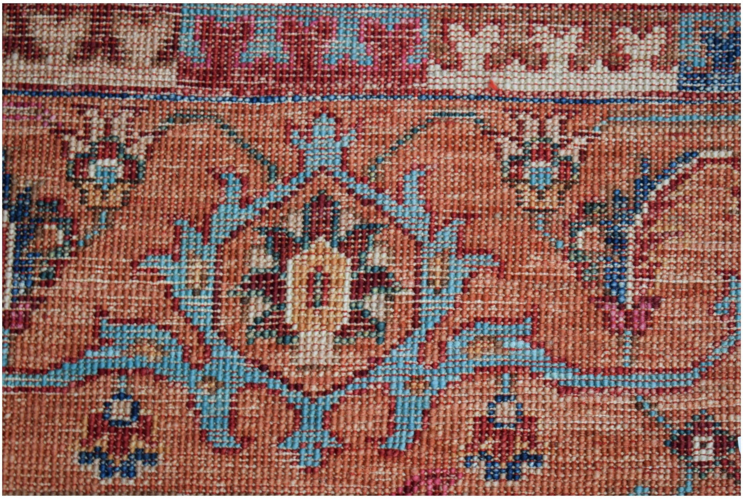 A close-up of an Afghan Chobi rug featuring intricate floral patterns in blue, red, and tan wool.
