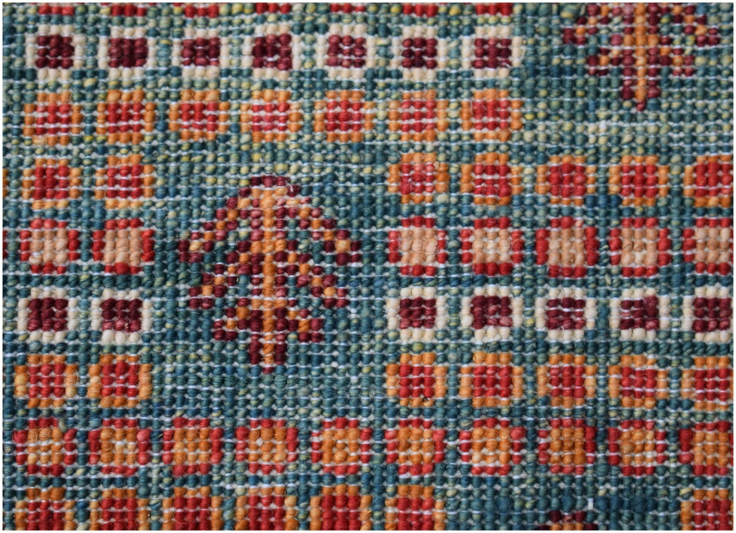A close-up of a handmade Afghan Chobi rug featuring a geometric grid pattern in earthy tones.