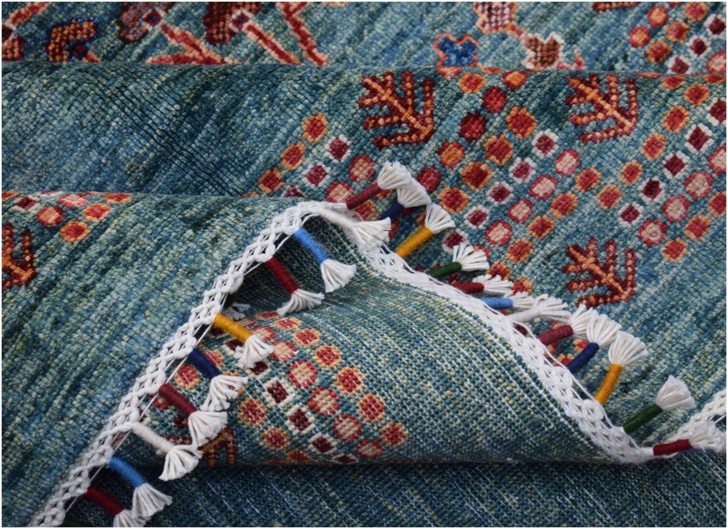 A handmade Afghan Chobi rug featuring a blue field with geometric patterns and colorful tassels.