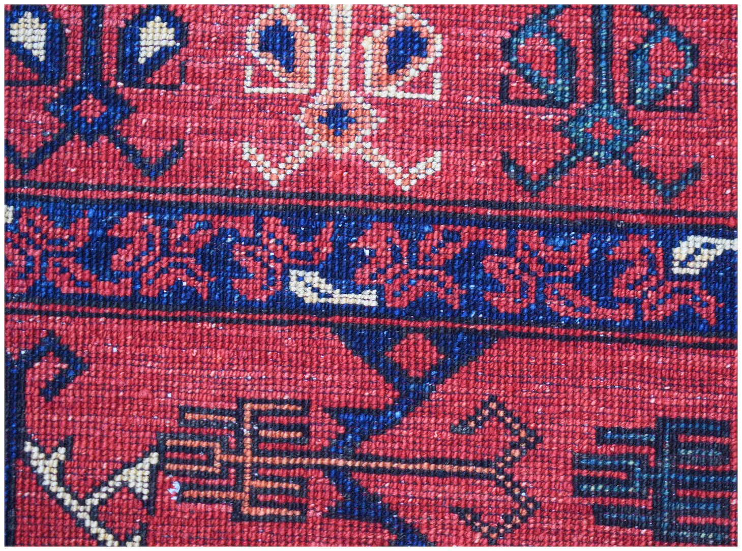 A close-up of a handwoven Afghan Chobi rug featuring traditional geometric patterns in red and blue.