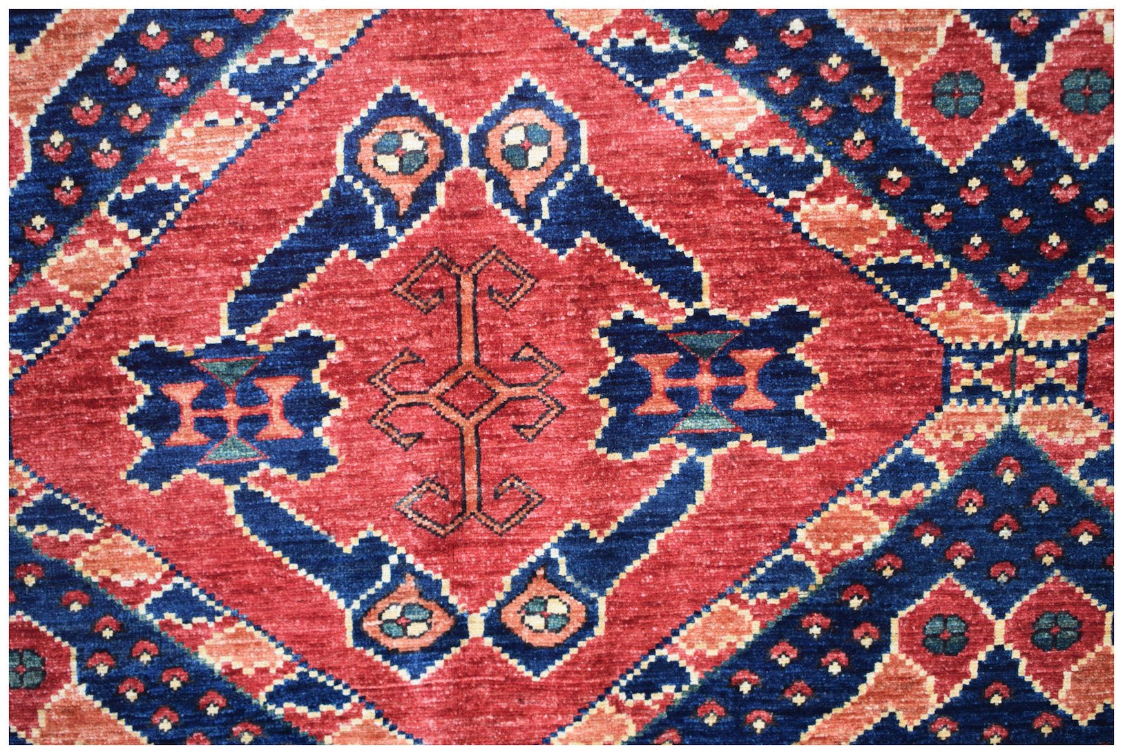 Handwoven Afghan Chobi rug featuring a geometric diamond pattern in red, blue, and earthy tones.