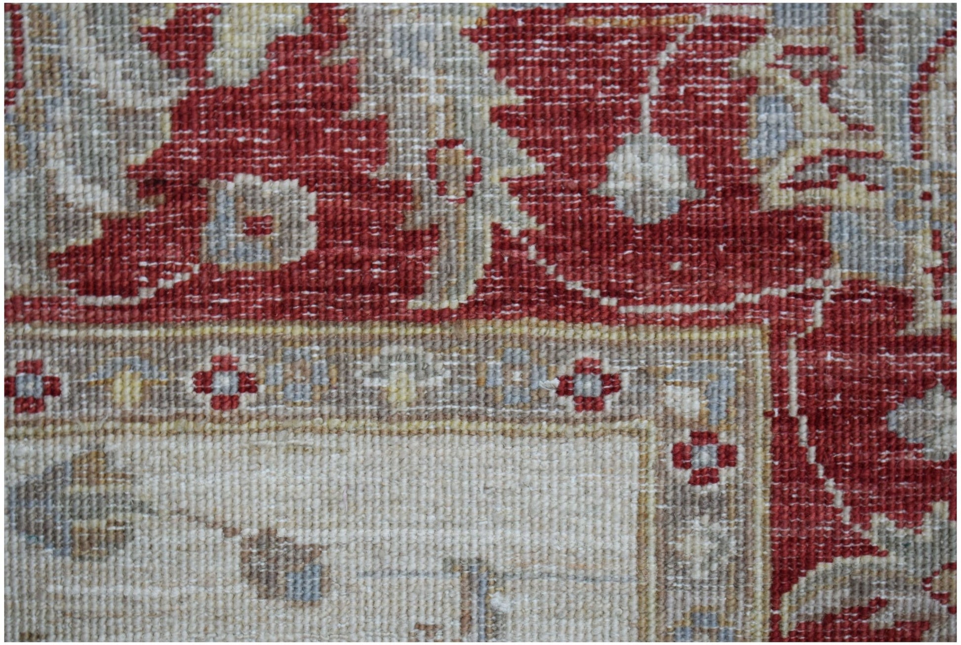 A close-up of a handwoven Afghan Chobi rug featuring traditional floral patterns in red and beige.