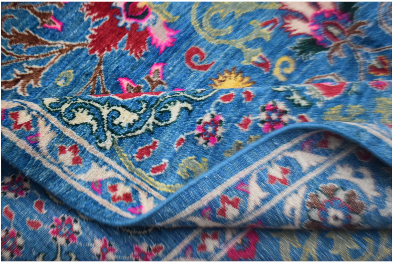 A handwoven Afghan Chobi rug featuring a vibrant blue field with intricate floral patterns.