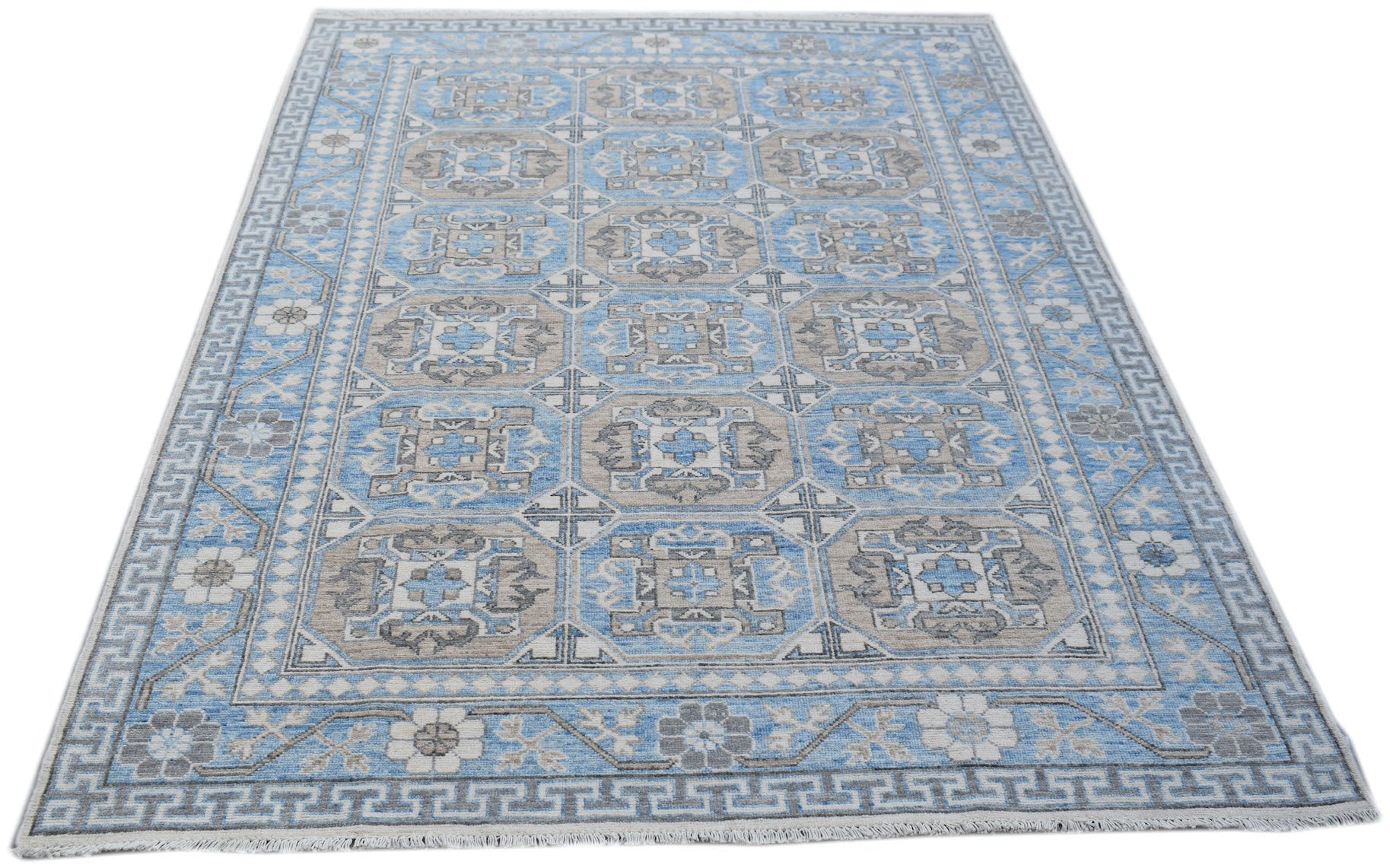 A handmade Afghan Chobi rug featuring a geometric pattern in shades of blue, grey, and cream.