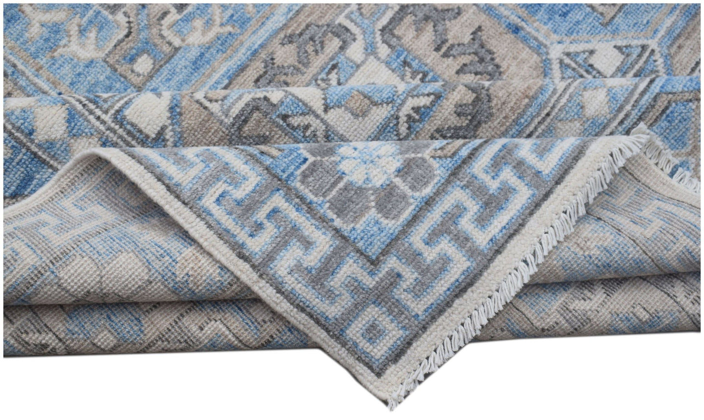 A handmade Afghan Chobi rug featuring a blue, grey, and beige geometric pattern with fringe.