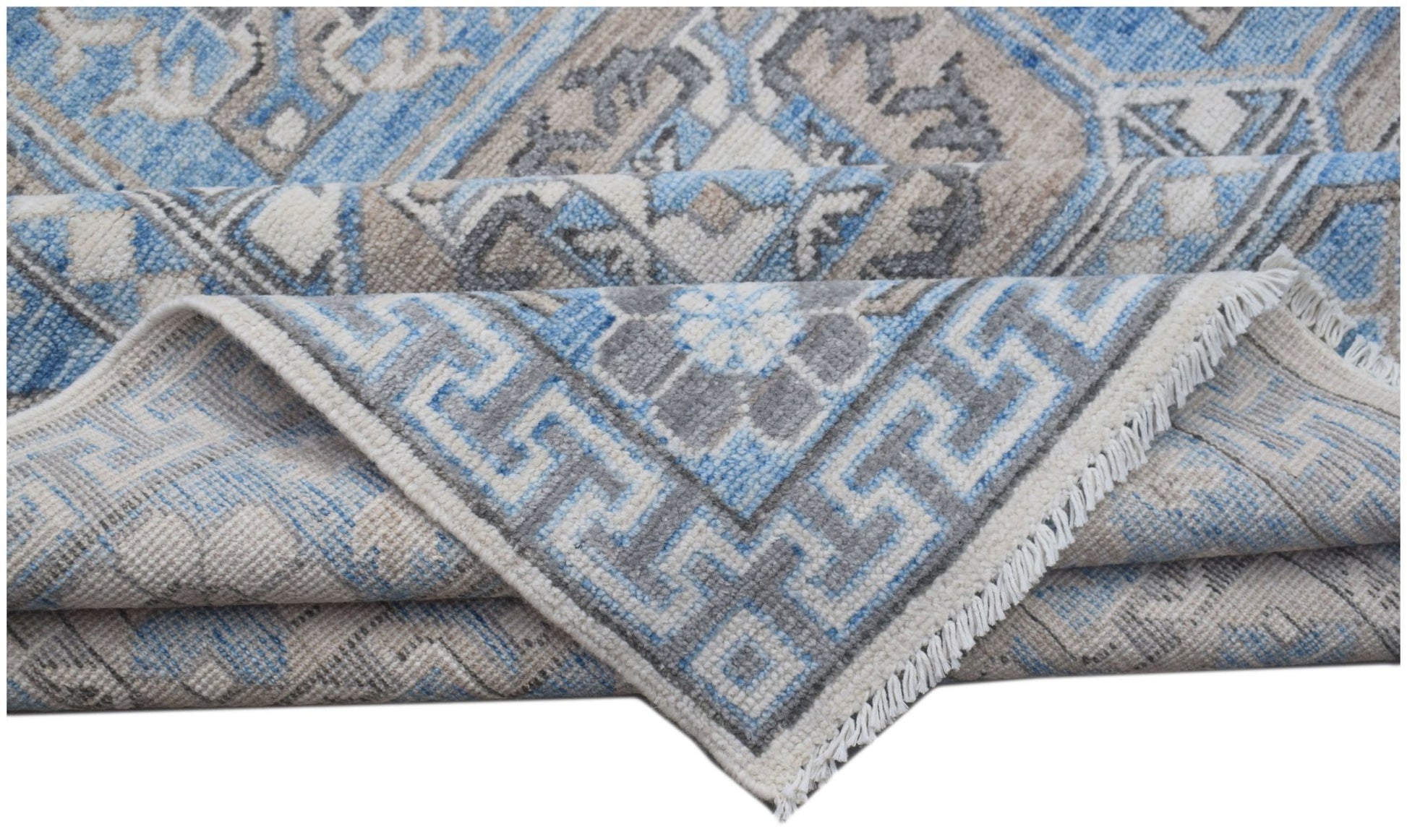 A handmade Afghan Chobi rug featuring a blue, grey, and beige geometric pattern with fringe.