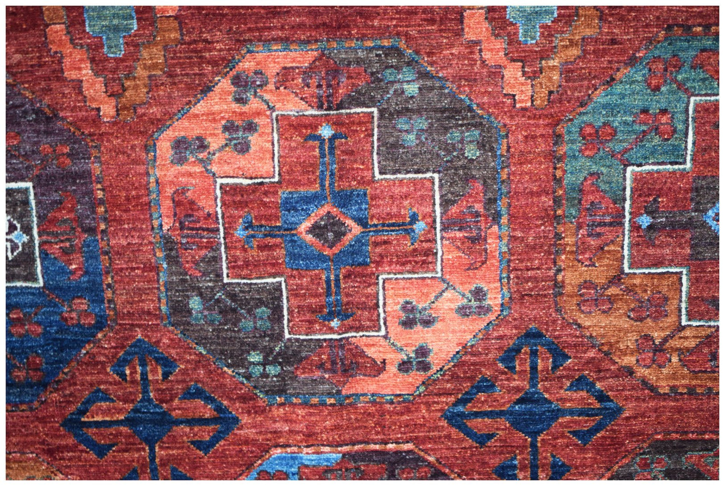 A handwoven Afghan Chobi rug featuring geometric patterns in shades of red, blue, and brown.