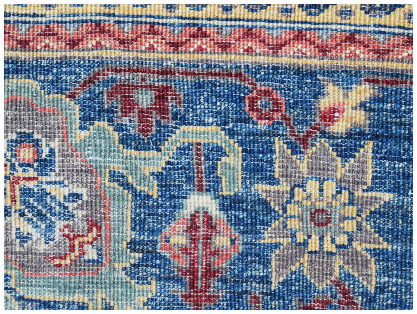 A close-up of a handwoven Afghan Chobi rug featuring intricate floral patterns in blue and red.