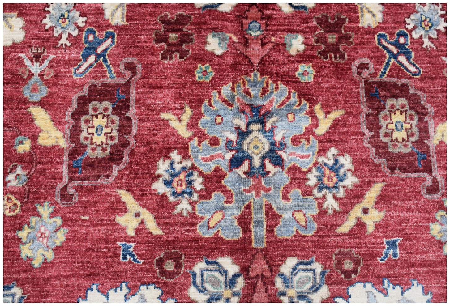 A handmade Afghan Chobi rug featuring a traditional floral pattern in red, blue, and cream tones.